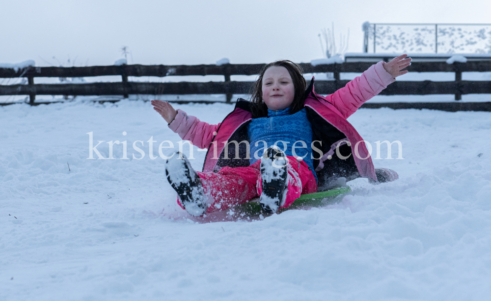 Kinder rodeln mit ihren Schneetellern by kristen-images.com