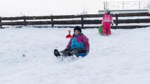 Kinder rodeln mit ihren Schneetellern