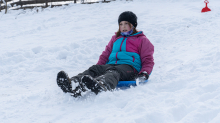 Kinder rodeln mit ihren Schneetellern