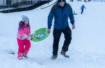 Kinder rodeln mit ihren Schneetellern